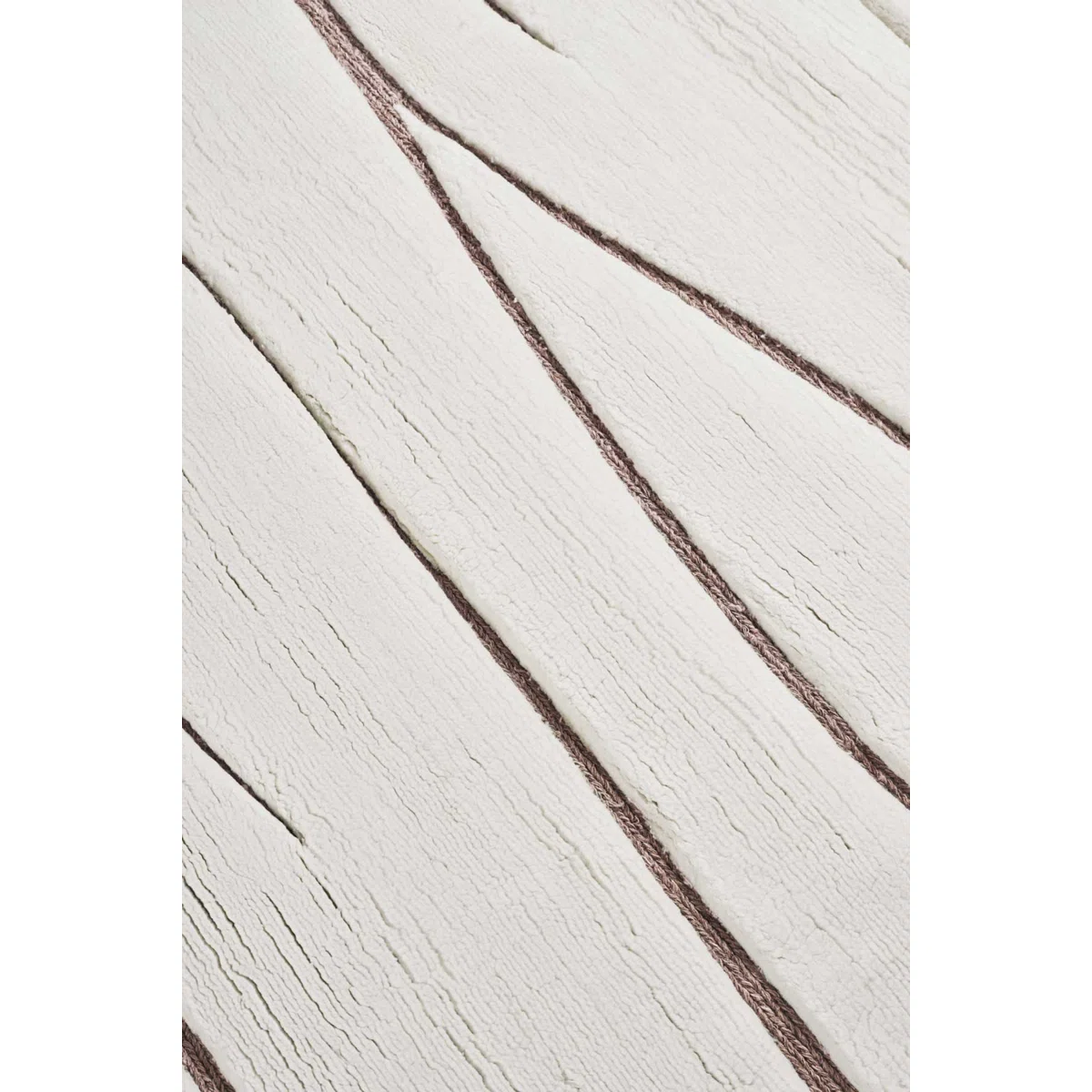 A close-up view of a textured white surface with irregular, wavy brown lines running diagonally across it, resembling an abstract or modern rug design.