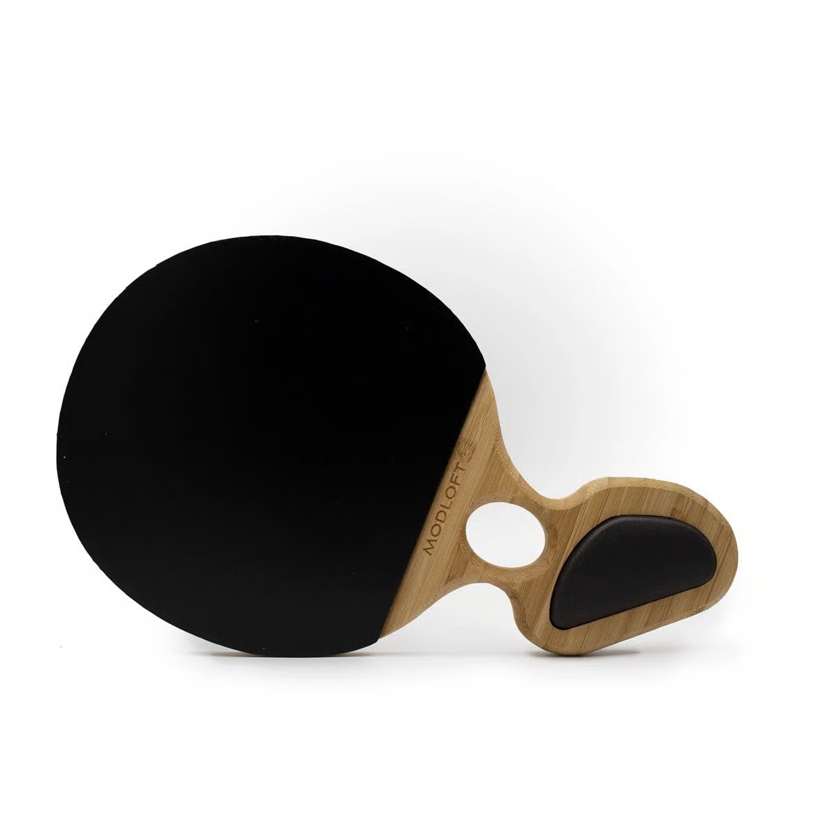 A modern table tennis paddle with a black rubber face and a wooden handle featuring a black ergonomic grip, resting on a white surface.