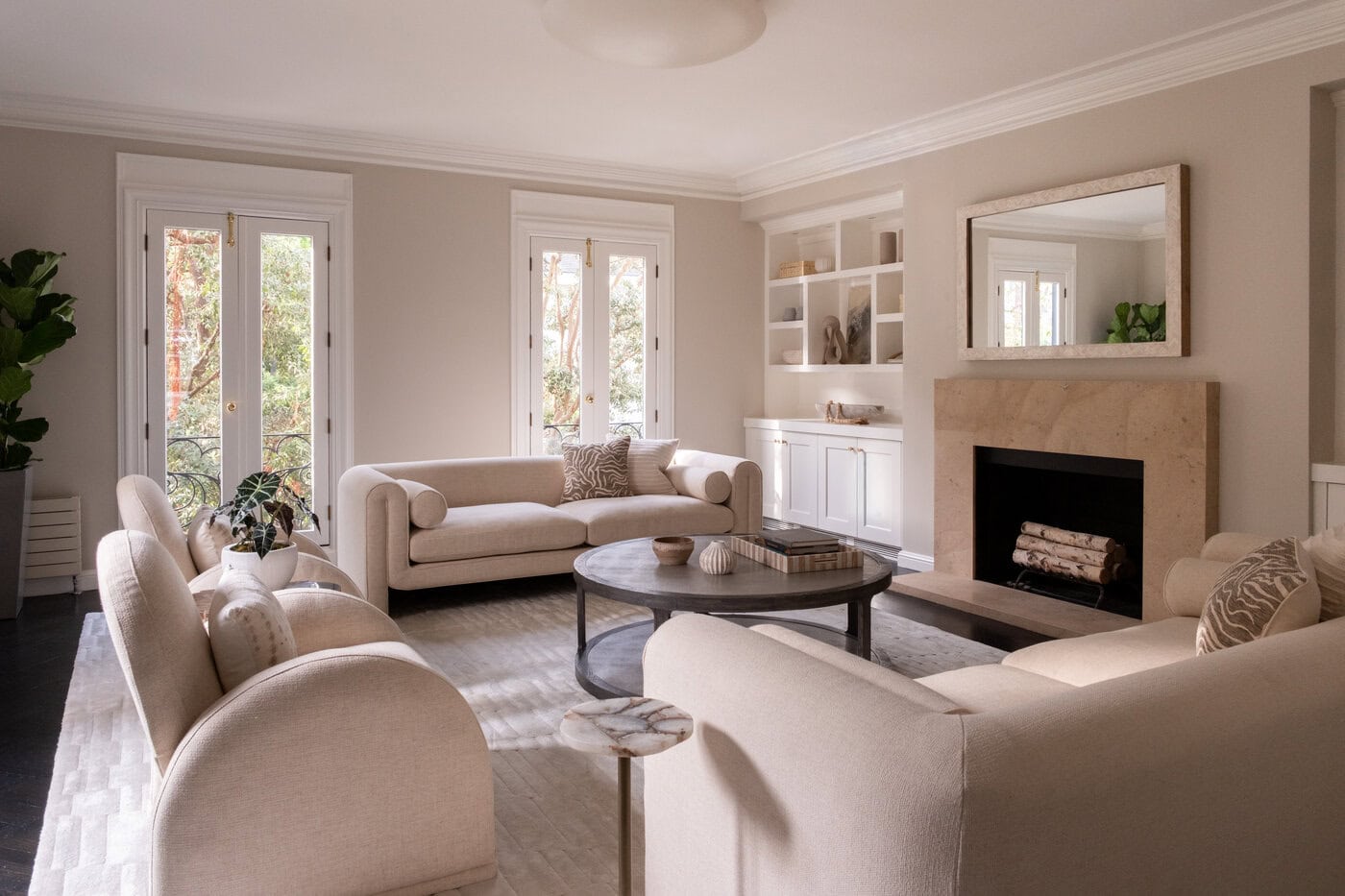 A Bright, Elegant San Francisco Living Room With Beige Sofas, A Round Coffee Table, Fireplace And Large Mirror, Built-In Shelves, And French Doors Leading Outside. Natural Light Fills The Space, Making It Perfect To Upgrade Your Lifestyle Or Sell With Ease.
